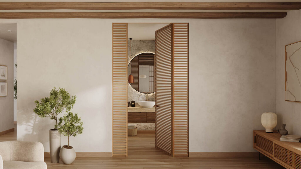Wooden swing door with vertical slats partially open, revealing a bathroom with round mirror and sink inside.
